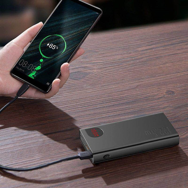 A smartphone is connected to a 10000mAh portable battery charger via a charging cable, utilizing 22.5W PD fast charging. The phone screen shows an 85% battery charge level. Both are placed on a wooden surface.