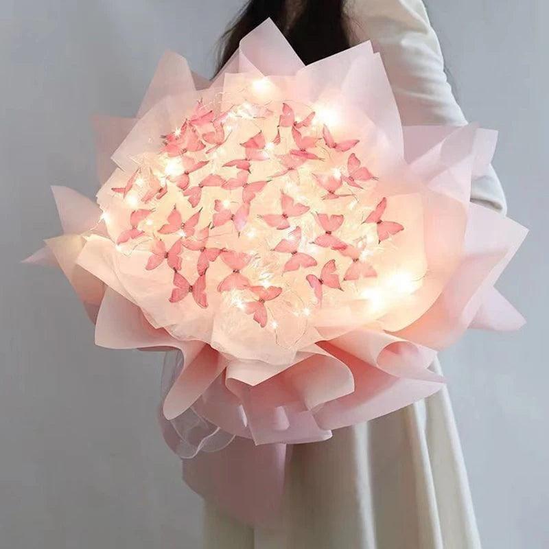 Someone holds a large bouquet wrapped in soft pink paper, featuring the versatile Butterfly Bouquets Butterfly Craft Supplies adorned with glowing lights and delicate pink butterflies. This butterfly arrangement creates an elegant and whimsical display, ideal for any setting.