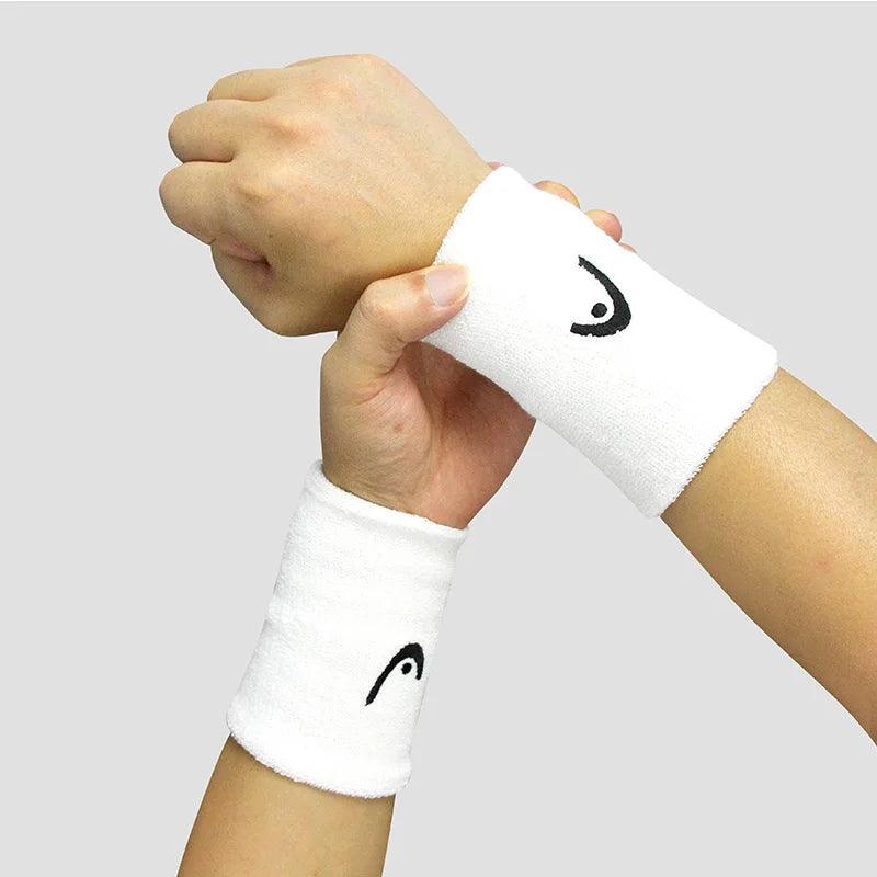 Two hands showcasing the Tennis Wristband, Badminton Sport Wristband, a must-have for tennis enthusiasts, featuring a small black logo set against a light gray background. Crafted from comfortable cotton, these wristbands ensure both style and performance.