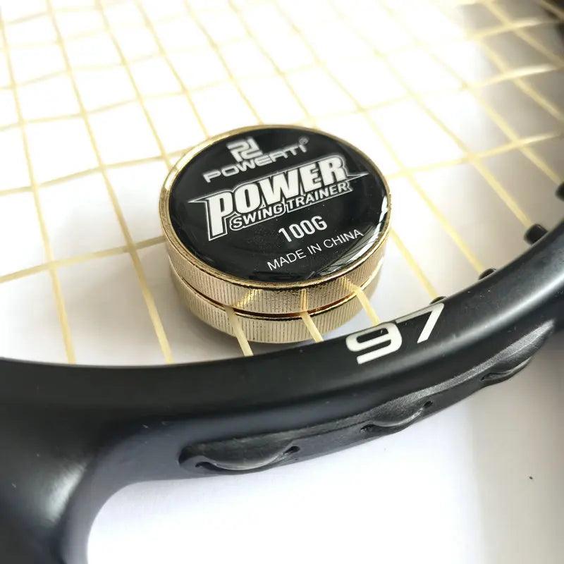 Close-up of a tennis racket with a round metal object labeled "TENNIS RACKET WEIGHT TRAINER 100G MADE IN CHINA" resting on the strings. Ideal for tennis players, this practice tool enhances strength in both serve and swing. The racket frame bears the number "97.