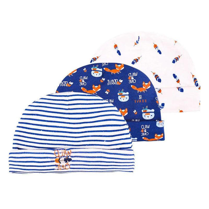 Three "Newborn baby hats" are displayed. The first hat features blue and white stripes with a small animal print. The second is adorned in blue with a playful fox and "WILD ONE" print. The third is white, showcasing a pattern of small orange foxes and blue accents, all crafted from soft cotton for newborns.