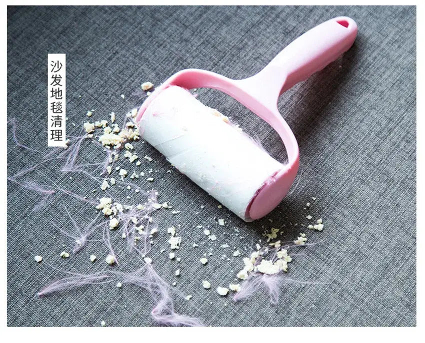 Pink washable wool roller cleaning pet hair and debris from a gray sofa.