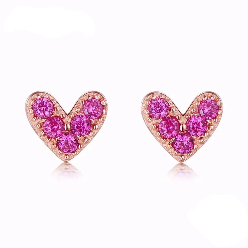 The Sterling Silver Hearts Rose Gold Pink CZ Fashion Jewelry features symmetrical heart-shaped stud earrings, adorned with small pink CZ stones set in gold-toned metal. Each heart boasts a vibrant design against a plain white background.