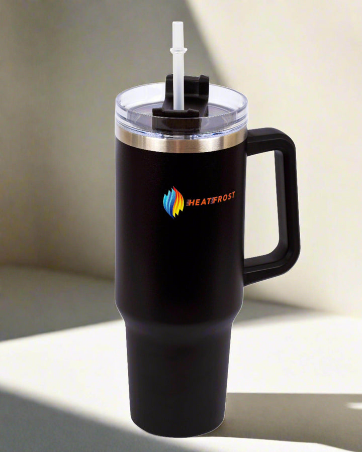 A 40oz large black Stainless Steel Tumbler with a handle, featuring an eye-catching colorful logo and the word "HEATFROST." This travel-friendly insulated beverage container comes with a clear lid and straw. The tumbler is gracefully placed on a light surface with elegant shadows.