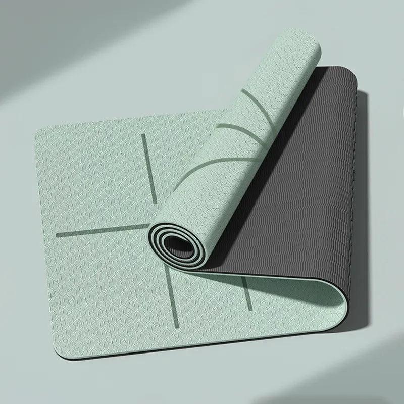 A partially unrolled Non-Slip Yoga Mam in mint green and dark gray lies on a light green surface, showcasing its eco-friendly TPE material. Its geometric patterns and alignment lines ensure a secure, non-slip practice.