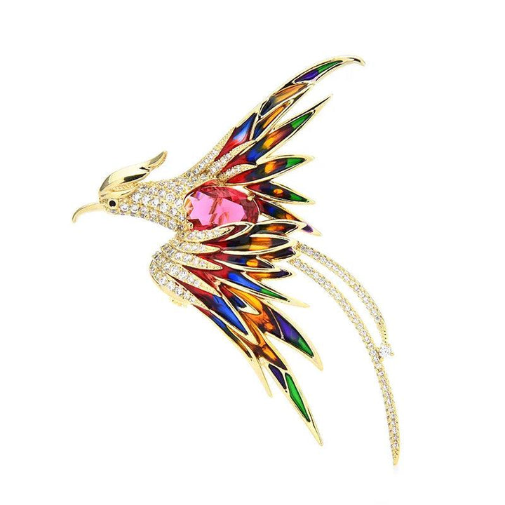 Introducing the Crystal Phoenix Bird Brooch from Wuli&baby—a vibrant statement piece perfect for parties. This colorful brooch is shaped like a phoenix, with its body embellished in gold and adorned with vivid gemstones in shades of red, blue, green, and orange. The intricately detailed wings and tail are highlighted by rhinestone metal, surrounding a large pink gemstone at the center to add extra shimmer.