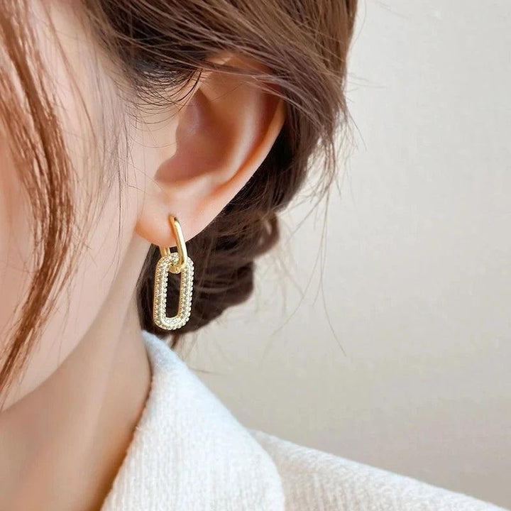 A close-up of a woman's ear adorned with Trendy U-shape earrings, showcasing a stunning geometric design in gold plating.