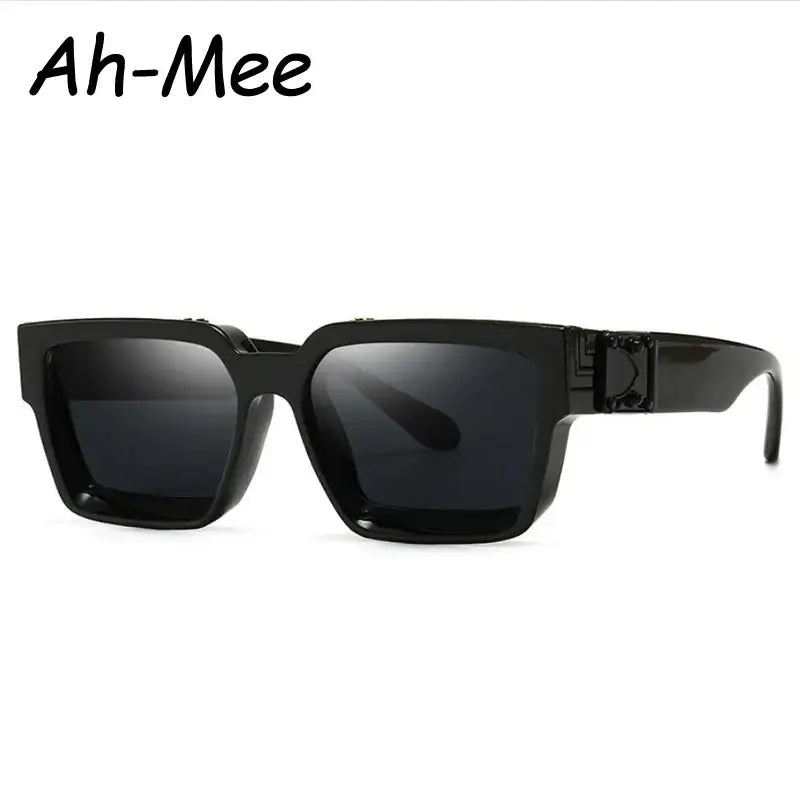 Black square sunglasses with polycarbonate lenses are set against a white background, showcasing an acetate frame with a striking geometric design. The brand name "Ah-Mee" is prominently displayed in the top left corner.