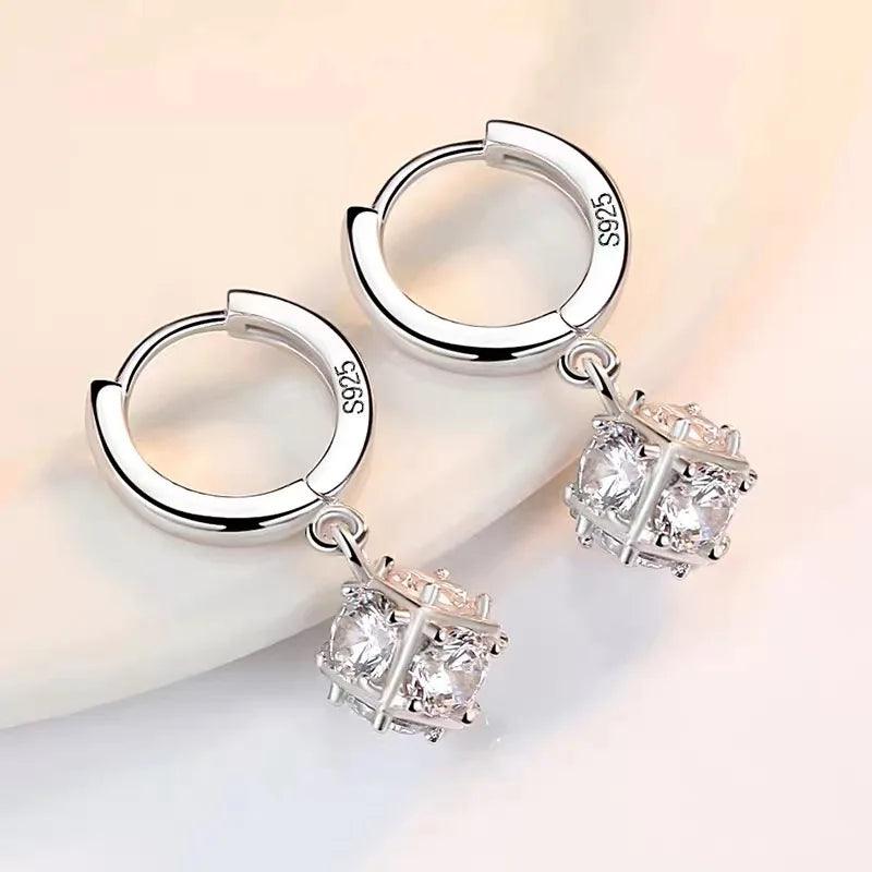 925 Sterling Silver Earrings Crystal Zircon Jewelry feature elegant hoop designs with cube-shaped dangle charms, each housing a sparkling stone within a metal framework. These stunning drop earrings are stamped with "925" to signify authentic S925 sterling silver and are beautifully presented against a light background.