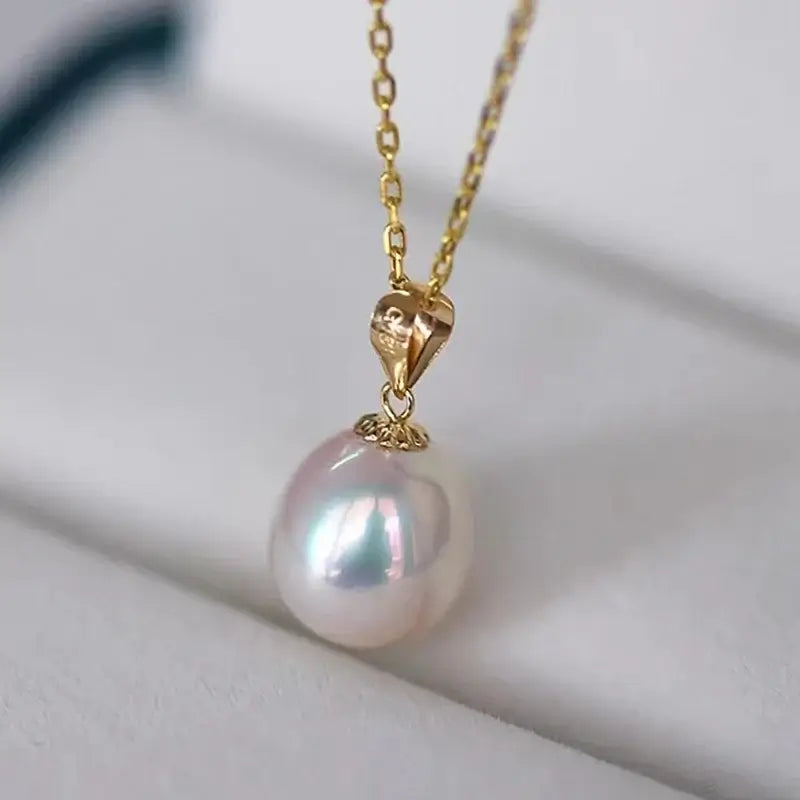 This detailed image highlights the Yellow Gold Natural Freshwater Pearl Pendant Necklace for Women from XF800 Jewelry, featuring a heart-shaped clasp and a glossy natural freshwater pearl pendant. The 18K gold harmonizes beautifully with the pearl's delicate tones, both presented elegantly on a light-colored surface.