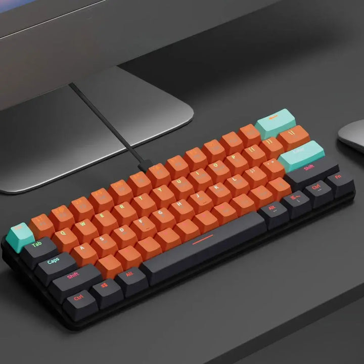 The Gaming Wired Keyboard is a compact, 61-key mechanical keyboard with a dark frame, featuring orange keys and pastel green keycaps on "Esc" and "Enter." It sits on a dark desk, offering hot-swappable red switches for customizable performance.