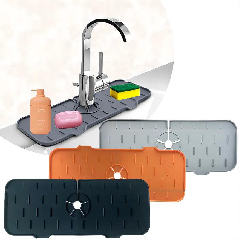 Displayed is a Faucet Guard kitchen sink mat, paired with a modern faucet. The eco-friendly gray mat, made of silicone material, holds a bottle, soap, and sponge. Additionally depicted are three more rectangular silicone mats in black, orange, and gray set against a white background.