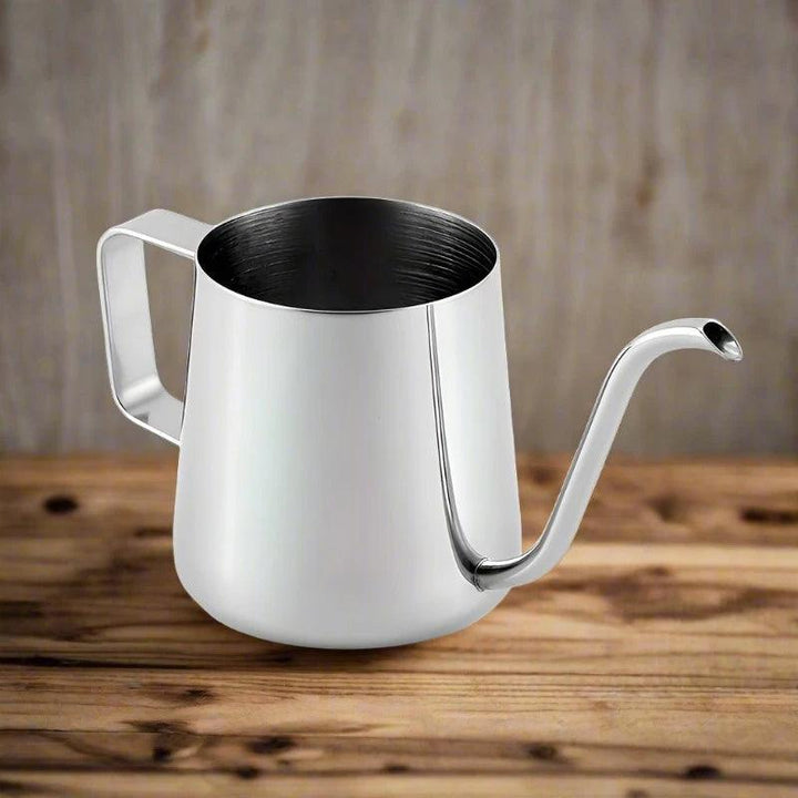 A product from the 304 Stainless Steel Milk Cup Coffee House Essential High-Quality Coffee Set, featuring a silver watering can that boasts a long, curved spout and a square handle, sits on a wooden surface. Its design mirrors that of a milk frothing cup, blending effortlessly into the blurred wooden background.