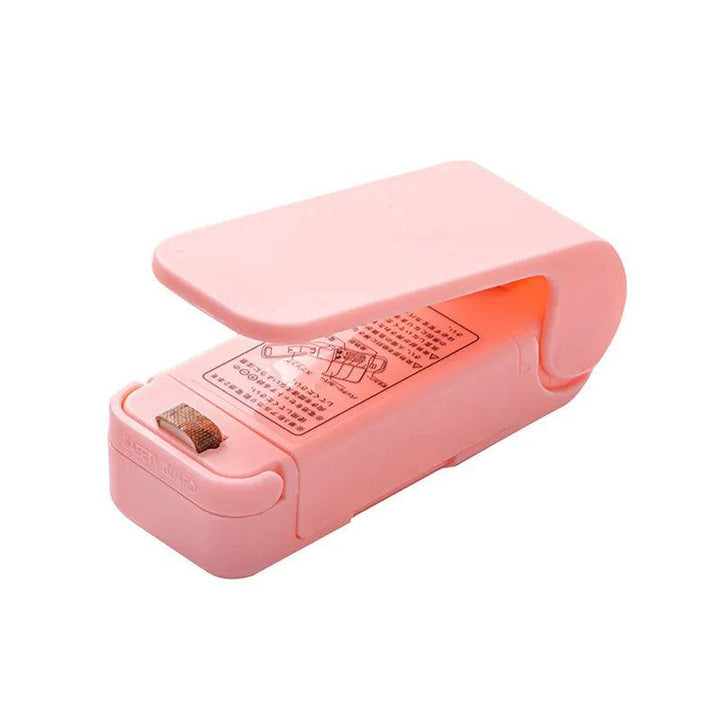 Introducing the "Heat Bag Sealer, Food Packaging Sealing Machine, Portable Snack Bag, Sealing Clip" in pink. This compact handheld tool is ideal for sealing food storage bags and comes with a metal heating element and printed instructions on the side. It's an essential device for preserving your food efficiently.