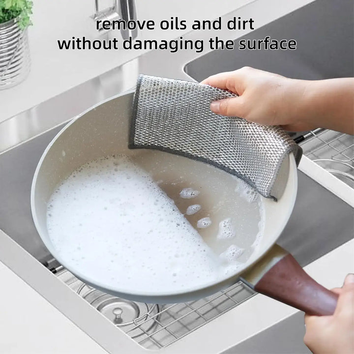 Person using Magic Cleaning Cloth to wash a pan in a sink, demonstrating its effectiveness in removing oils and dirt without damage.