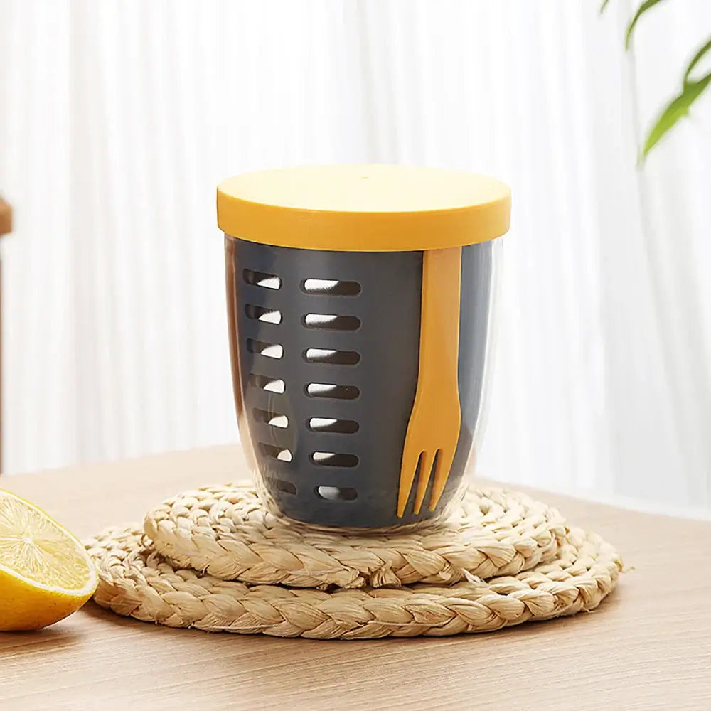 A glass container, complete with a yellow lid and fork, elegantly sits on a straw coaster, designed as an eco-friendly, leak-proof salad box similar to the "Fruit Cup with Fork Portable Picnic Bottle Large Capacity Storage Plastic Cup Sealed Leak Proof.