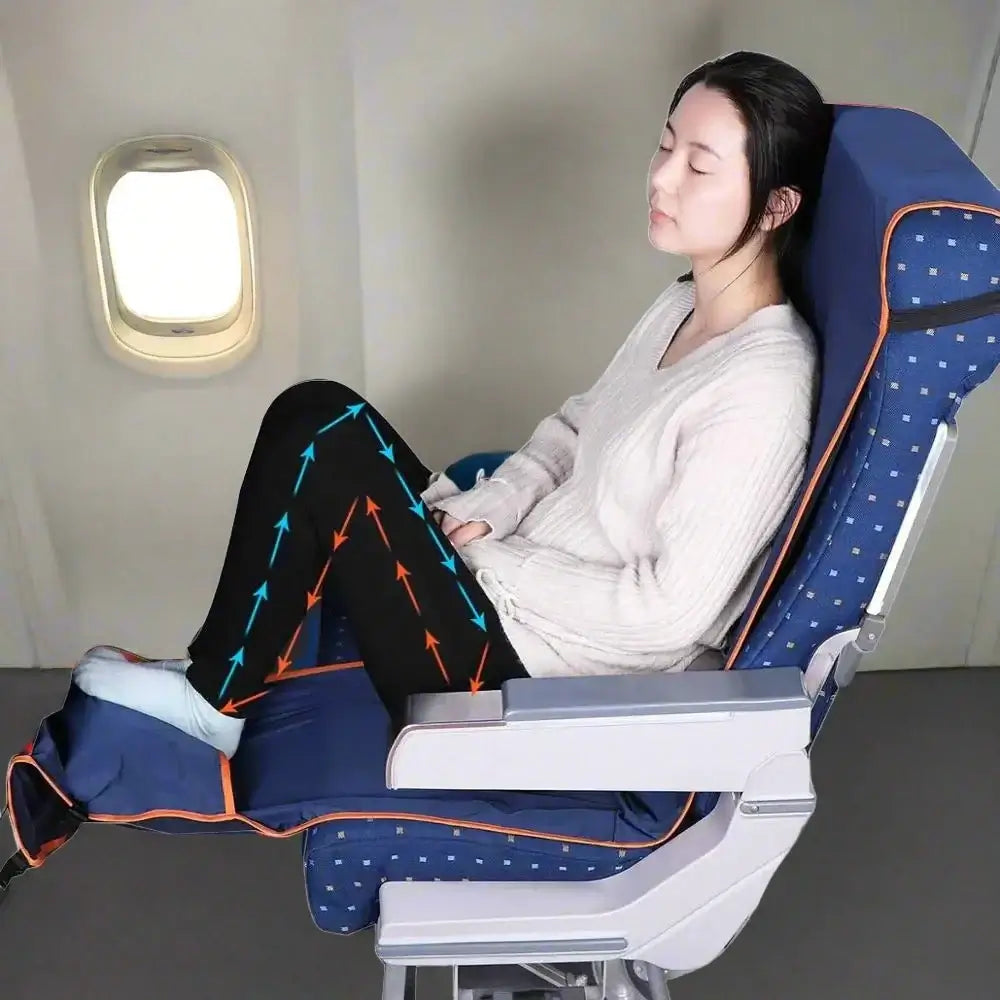 A person is comfortably reclined in an airplane seat, their eyes closed while wearing a sweater and leggings, accentuated by a travel accessory. Arrows highlight the massage effects on the legs. The navy blue seat with orange accents is enhanced by the Adjustable Footrest Inflatable Pillow for Travel Airplane Footrest, providing additional comfort with its adjustable footrest feature.