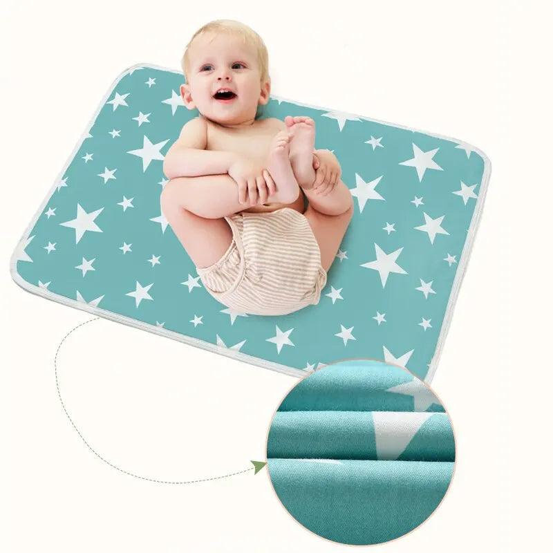 A smiling baby wearing a diaper is lying on a "Small size diaper mat" with a design of white stars, featuring the comfort of the "Breathable waterproof mattress." A circular inset showcases the fabric's texture. The baby playfully lifts their feet against a plain, light-colored backdrop.