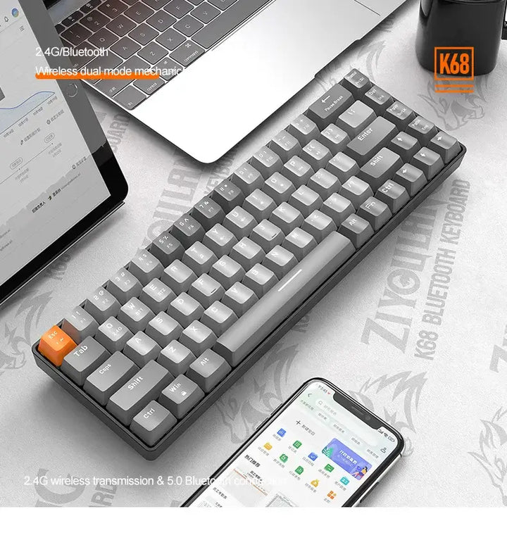 A Wireless Keyboard Bluetooth Dual Mode, featuring a sleek gray design with white and gray keys and a standout orange key, sits compactly on a desk next to a laptop and smartphone. The image emphasizes its wireless dual-mode and Bluetooth capabilities, illustrating an ideal combination of style and functionality for any workspace.