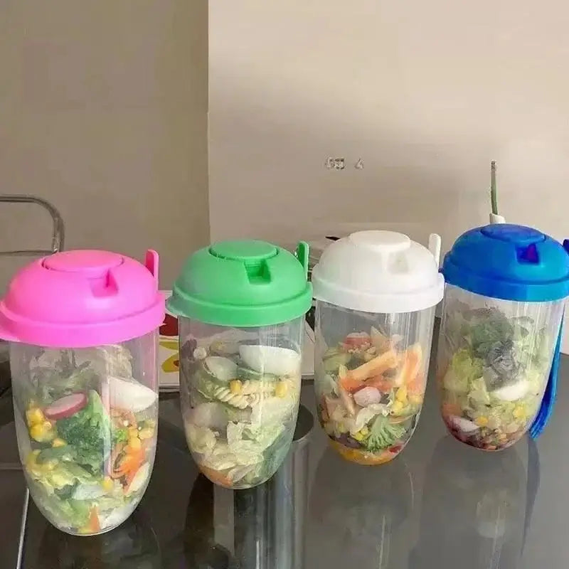 A set of four Portable Salad Cups, each featuring a colorful lid in pink, green, white, and blue, is filled with fresh vegetables including lettuce, corn, broccoli, and carrots. Arranged neatly in a row on a reflective surface, they elegantly display their vibrant and healthy contents.