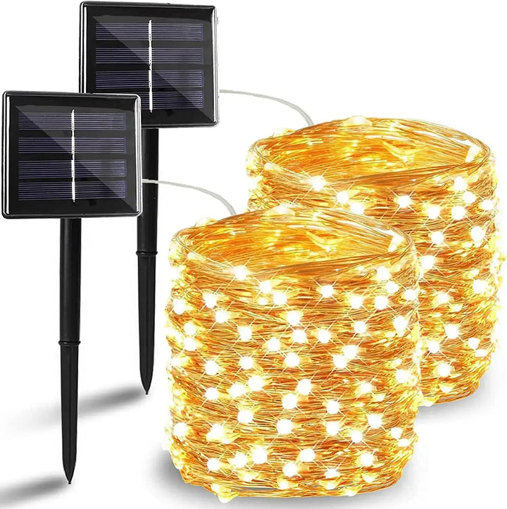 The LED Solar Light Outdoor with Waterproof capabilities features two coils of warm white solar-powered string lights, complete with black ground stakes that are topped by solar panels for charging. The LED bulbs are neatly bundled, making them ideal for decoration or outdoor use.