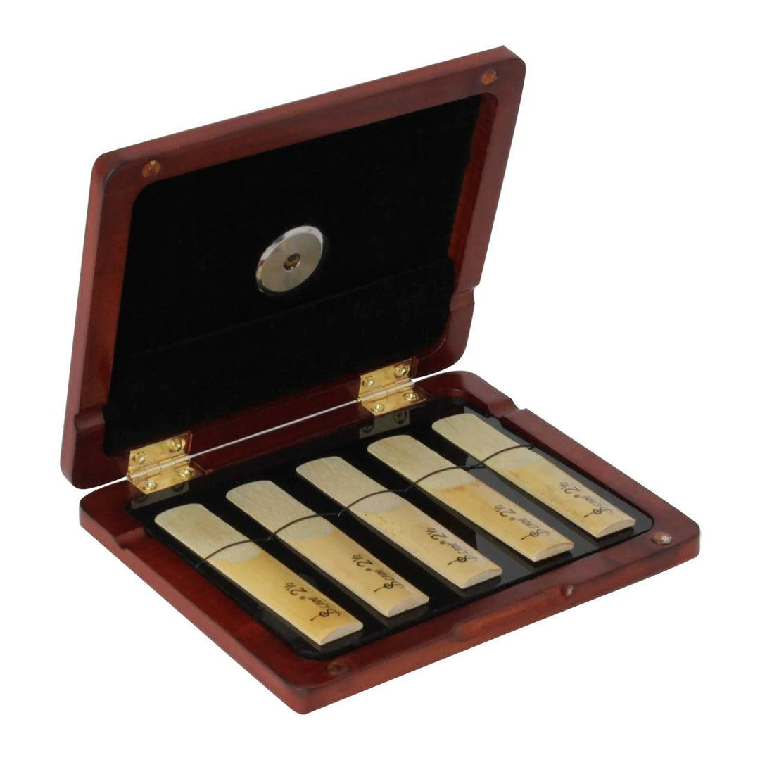 The Wooden Reed Case, also known as the Saxophone and Clarinet Reed Storage Case, features a luxurious black velvet interior that holds six reeds neatly in individual slots. When opened, it showcases its contents with enhanced reed protection features and includes a hygrometer to maintain optimal moisture control.