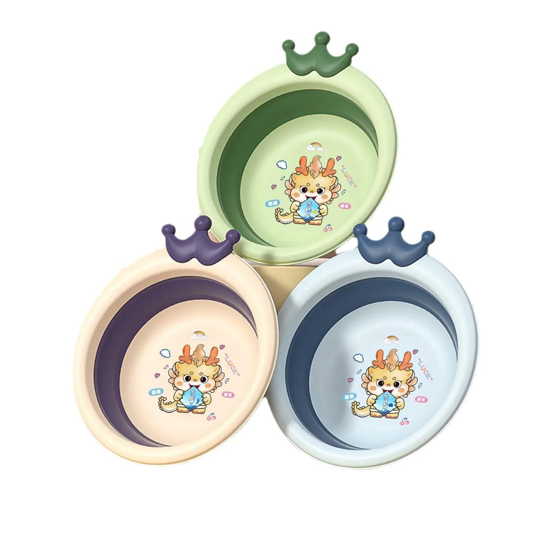 Three foldable baby basins with crown-shaped handles in pastel green, peach, and blue form a triangle. Each versatile bathing solution showcases a cartoon giraffe holding a bottle amid stars and bubbles, making for compact storage when not in use.