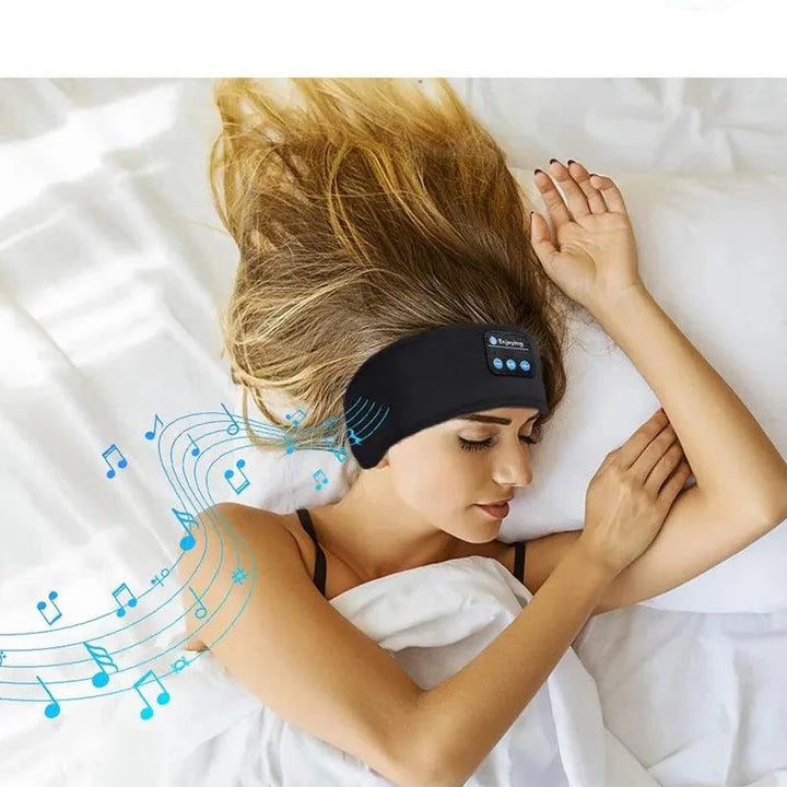 A woman with long blonde hair sleeps on a bed, wearing a black Sport Sleep Headband with buttons. Blue music notes are illustrated around her, suggesting she is listening to music through her Wireless Bluetooth Headset with advanced noise-cancellation technology.