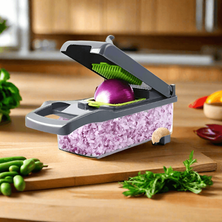 A 14/16-in-1 Vegetable Slicer Cutter with Basket on a countertop effortlessly dices a purple onion. Surrounding it, fresh herbs, green beans, and sliced red and yellow peppers create a vibrant display in the warm kitchen setting with wooden cabinets.