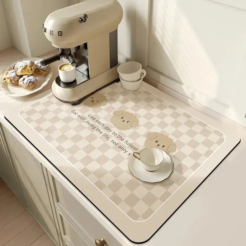 Kitchen countertop with antiskid quick dry diatom mud mat featuring cute design next to coffee maker and pastries.