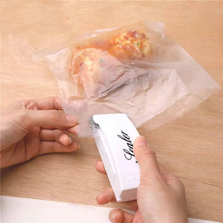 Hands expertly sealing food storage bags with the white "Heat Bag Sealer, Food Packaging Sealing Machine, Portable Snack Bag, Sealing Clip." Inside, the bag holds delicious pastries resting on a wooden surface, preserving their freshness like a true food-saver.