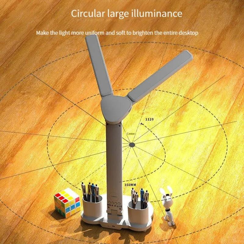 The LED Desk Lamp USB Rechargeable Dimmable Reading Light features three adjustable blades to illuminate a wooden surface. Below it, there are compartments containing pens and a small toy rabbit figure, with a colorful cube puzzle placed nearby. Concentric circles and measurements illustrate the light's spread to ensure eye protection.