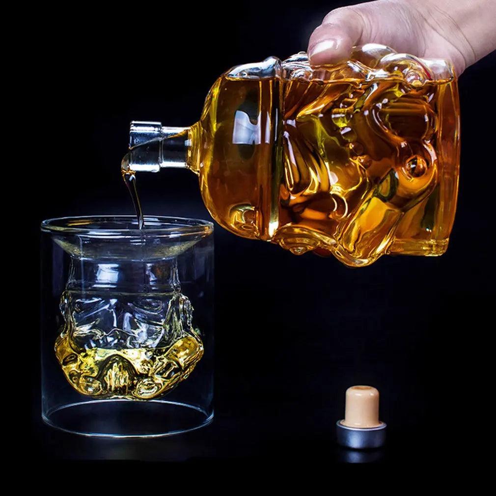 Using a skull-shaped whiskey decanter, someone pours the amber liquid into a glass featuring a design reminiscent of the iconic Storm Trooper helmet. Set against a dark background, this scene emphasizes the intricate details of the "Storm Trooper helmet wine glass" from the "Whiskey decanter set," offering a Star Wars-inspired drinking experience with these "Galactic drinking glasses.