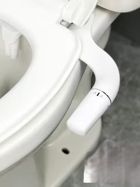 The Bidet Attachment Non-Electric Sprayer Hygienic Cleaning Solution includes a white toilet seat with a non-electric sprayer and control. The bidet control is marked with various hygienic cleaning settings, and the surrounding area offers partial glimpses of the sleek white toilet surface.