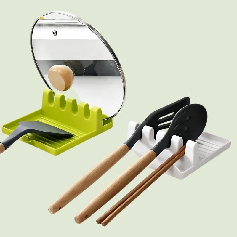 Displayed is a set of Folding Spoon Holders featuring green and white designs. The green holder accommodates a pot lid and spatula, while the white holder keeps a spatula, spoon, and wooden chopsticks secure against a pale green background.