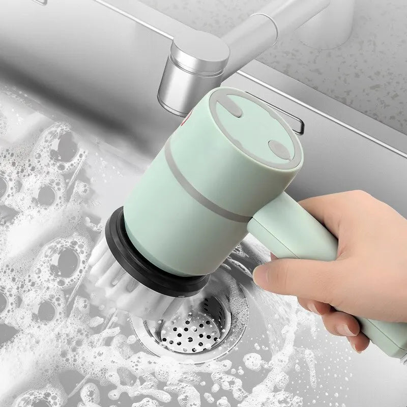 A hand wields the mint-green Cordless Electric Bathroom, Kitchen & Sofa Cleaning Brush, efficiently scrubbing a stainless steel kitchen sink with soap and bubbles. The multi-functional tool tackles grime as the sink faucet glimmers in the background.