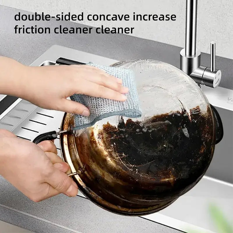 Person using double-sided magic cleaning cloth to scrub a burnt pot in the kitchen sink.