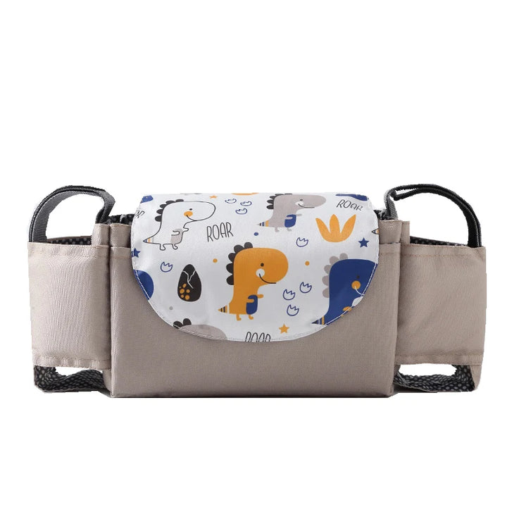 A beige "Stroller bag organizer" crafted from durable nylon fabric with a colorful dinosaur-themed flap featuring playful illustrations and the word "ROAR." This multifunctional "Portable travel storage for carriages" offers ample storage space with black mesh pockets on the sides.