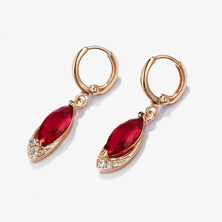 Gold hoop earrings featuring marquise-shaped red gemstones and small clear crystals, beautifully accented by sparkling zirconia stones. The gemstones dangle elegantly from each hoop, highlighted against a plain white background, embodying the style of Real Tibetan Silver Earrings with round cut zirconia stones in elegant sterling silver jewelry.