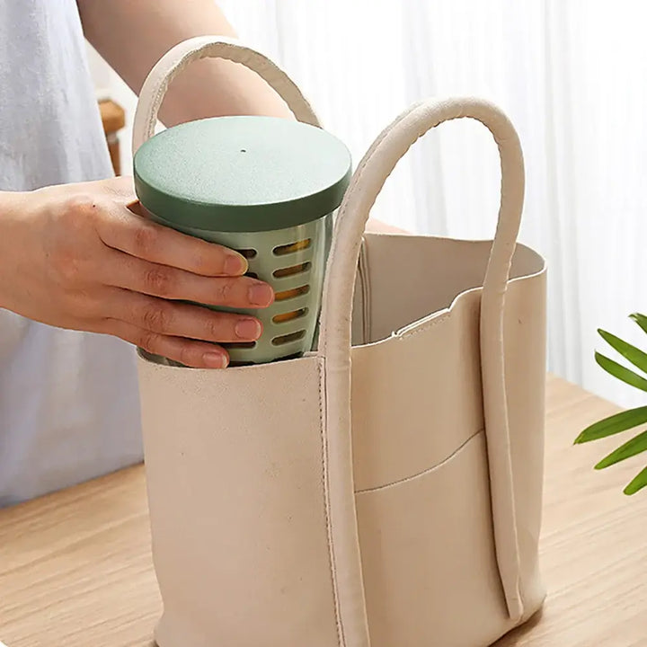 A person holding an eco-friendly bag stands beside the "Fruit Cup with Fork Portable Picnic Bottle Large Capacity Storage Plastic Cup Sealed Leak Proof," ready to take on the day with spill-free storage solutions.