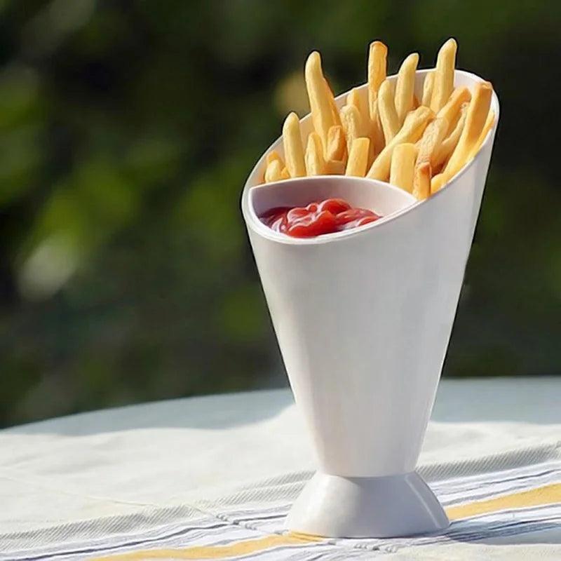 On an outdoor table set against a blurred green backdrop, a Sauce Storage Dish and Snack Dipping Cup hold crispy french fries alongside their complementary side of ketchup.