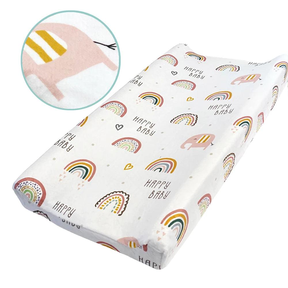 The foldable travel baby changing mat, crafted from minky dot fabric, features vibrant designs of rainbows, hearts, and a playful striped animal illustration. It is adorned with the repeating text "Happy Baby" across its surface, with a detailed circular close-up that highlights the delightful pattern. Ideal for on-the-go convenience as a reusable changing pad cover.