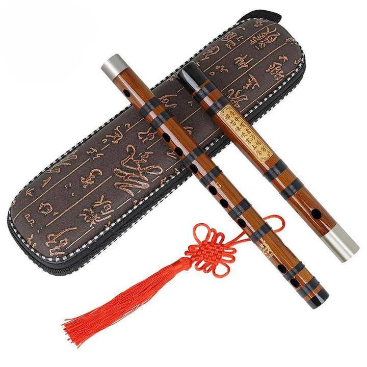 A Bamboo Flute Chinese Musical Instrument Traditional Flute, featuring metal caps and a decorative red tassel, is placed next to an intricately designed case embellished with Asian characters.