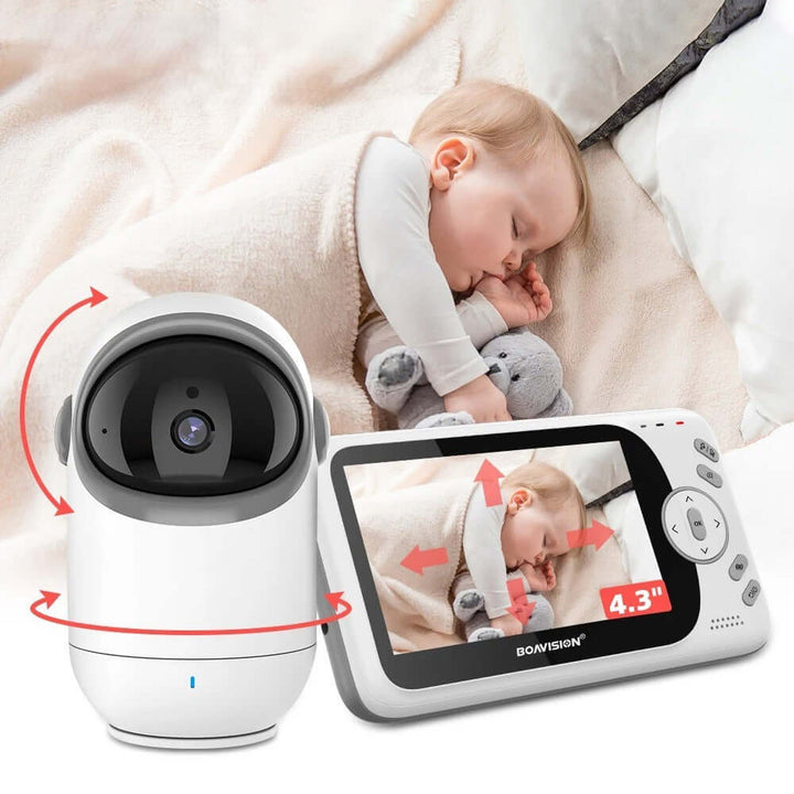 A baby rests on a bed, snuggling a plush toy. In the foreground, there is a Video Baby Monitor with a screen showing the sleeping infant. This monitor features motion controls for rotating its Tilt Camera and includes night vision for clear viewing even in low light conditions.